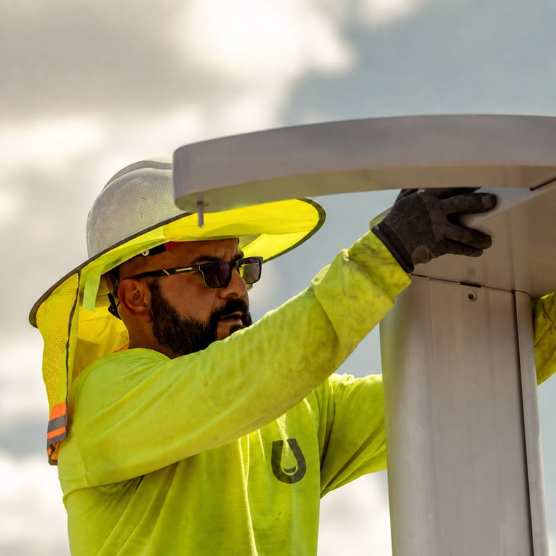 Technician fitting the housing onto an EV charger pedestal during a commercial installation